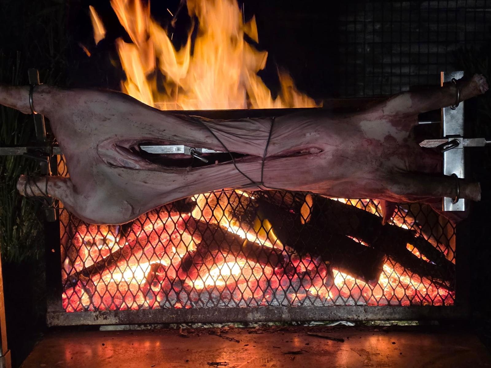 Cochon à la broche au feu de bois, flammes spectaculaires la nuit