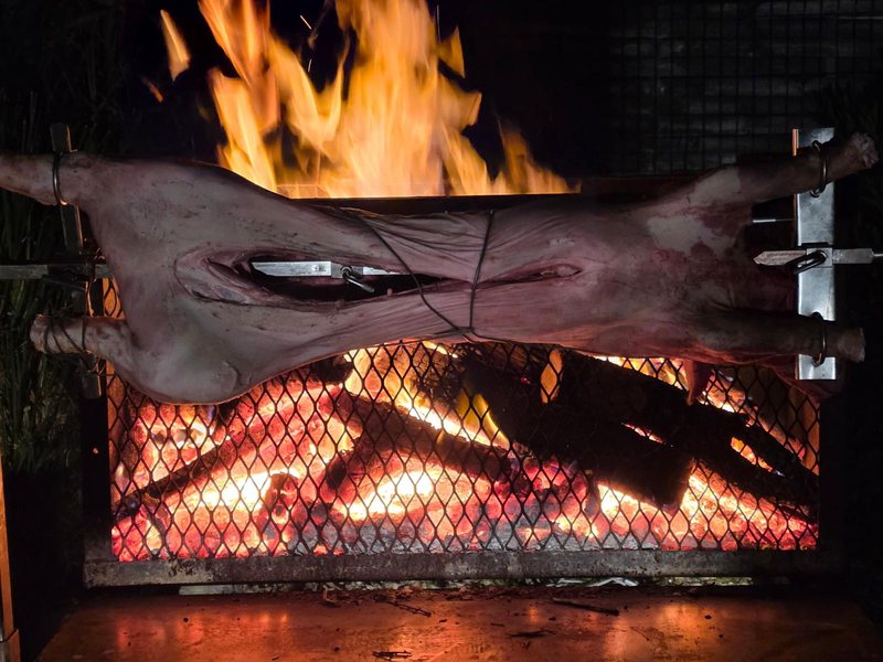 Cochon à la broche au feu de bois de nuit, flammes spectaculaires